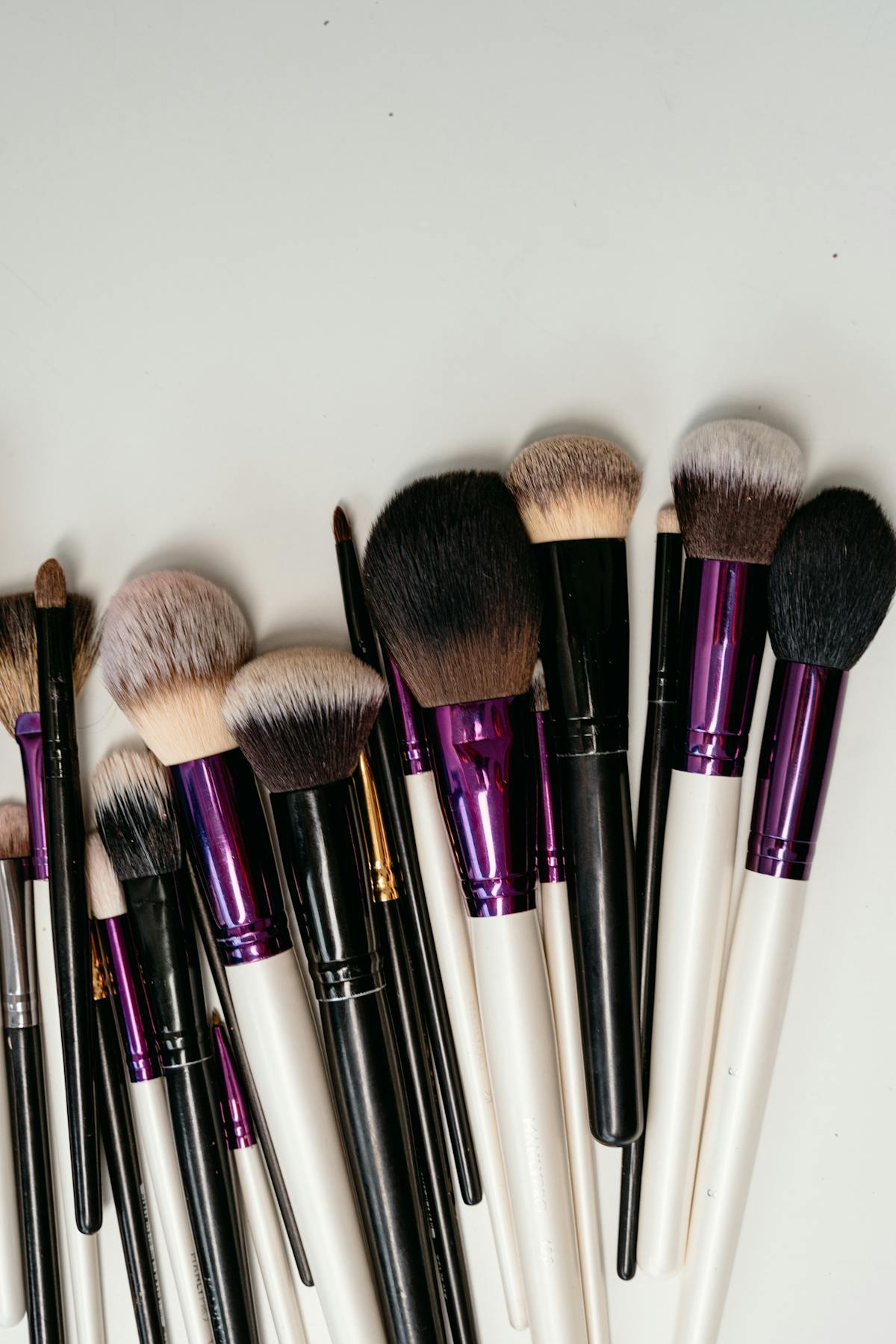 Collection de pinceaux de maquillage disposés sur une surface claire