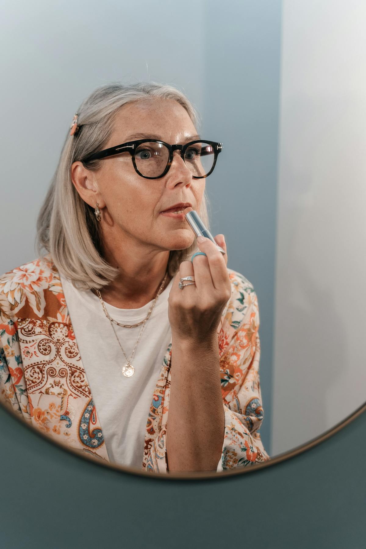 Femme de 60 ans appliquant un rouge à lèvres lumineux