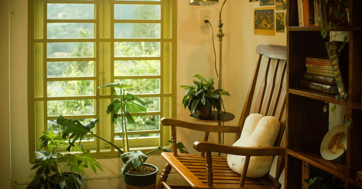 Coin lecture cosy avec fauteuil, plaid, lampe douce et bibliothèque dans un intérieur chaleureux