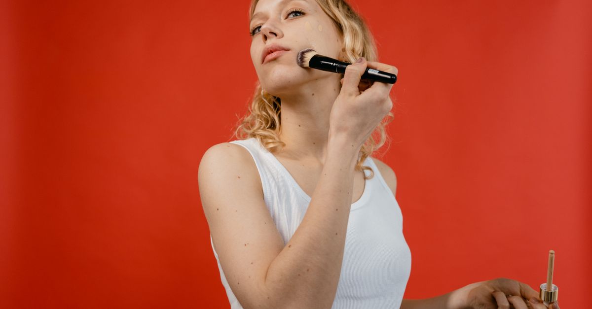 Femme appliquant un fond de teint devant un miroir