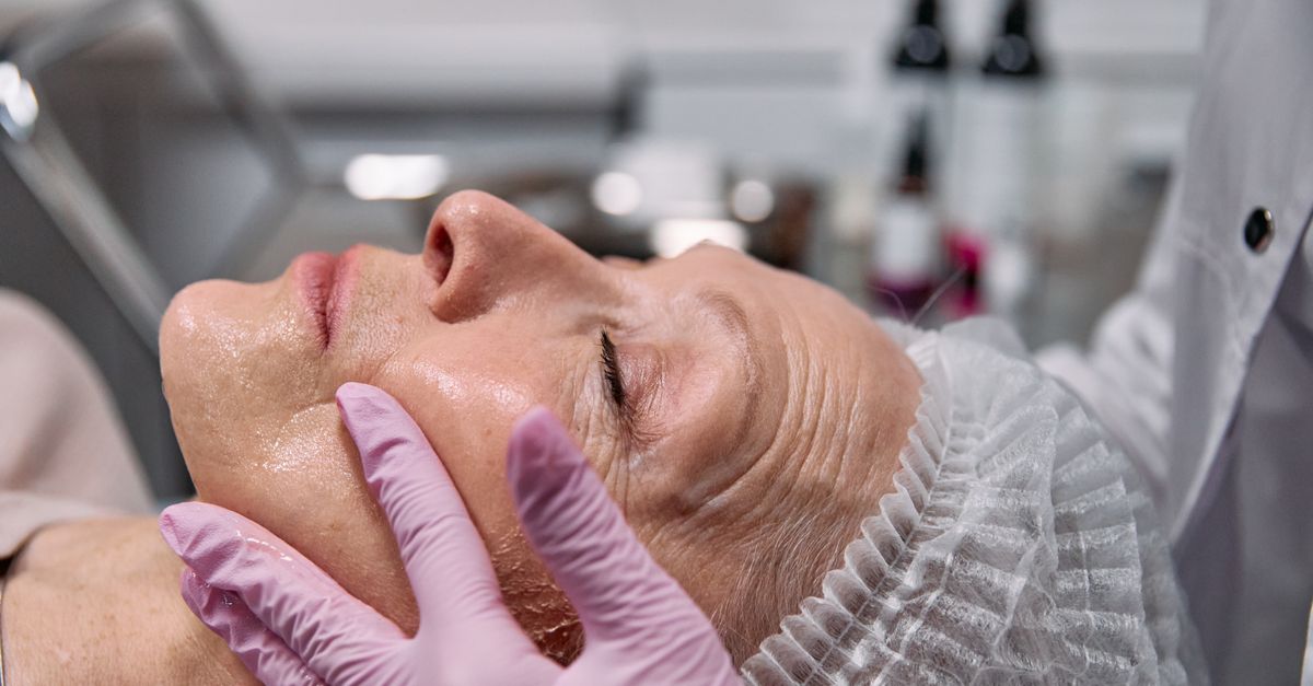 Femme appliquant un soin anti-âge sur le visage devant un miroir