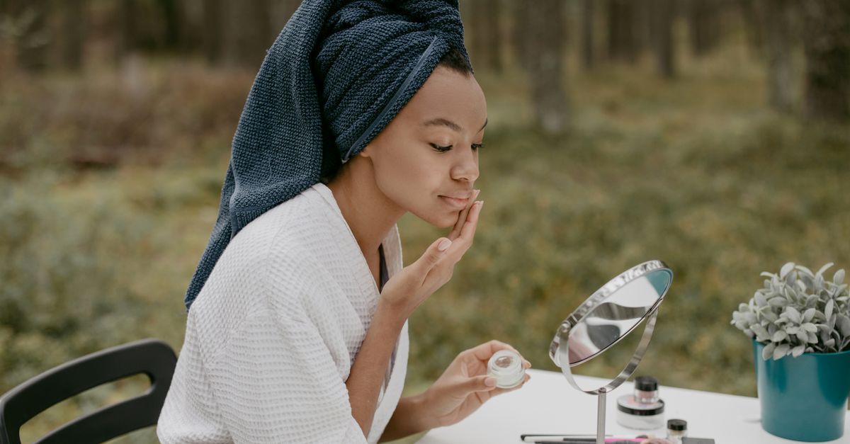 Femme observant sa peau devant un miroir dans une salle de bain lumineuse